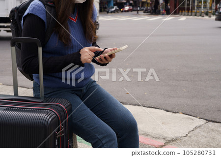 Woman with baggage in downtown city street ordering taxi using smart phone app Booking taxi using application online on smart phone. 105280731