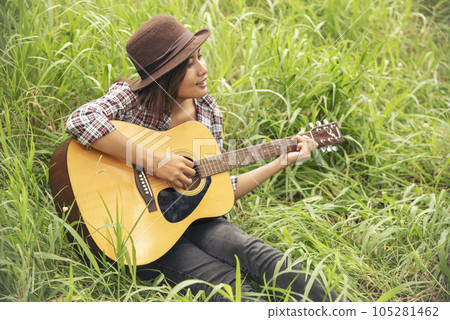 Young women playing acoustic guitar outdoor in green park. Woman person playing acoustic guitar music instrument at home, young Asian musician girl lifestyle in beautiful nature. Happy guitarist Young women playing acoustic guitar outdoor in green park. Woman person playing acoustic guitar music instrument at home, young Asian musician girl lifestyle in beautiful nature. Happy guitarist 105281462