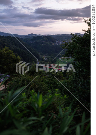 Summer 2023 Tsukigase evening view Tsukigase Bridge and a distant view (vertical) seen through thick plum trees Summer 2023 Tsukigase evening view Tsukigase Bridge and a distant view (vertical) seen through thick plum trees 105281884
