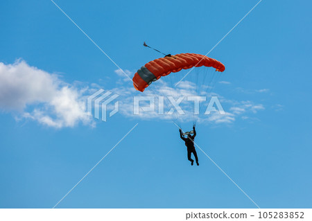 Parachute in the sky. Skydiver is flying a parachute in the blue sky Parachute in the sky. Skydiver is flying a parachute in the blue sky 105283852