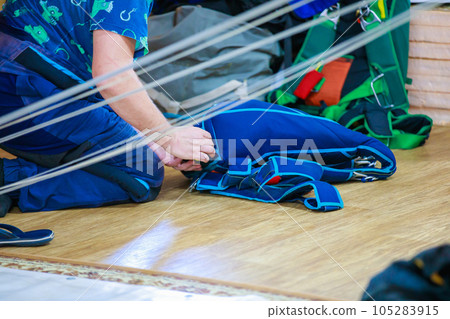 Packing a parachute into a backpack. Packing a parachute into a backpack. 105283915