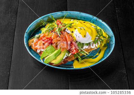 Belgian waffle with avocado, salmon, poached egg, tomatoes, greens and cheese sauce 105285336