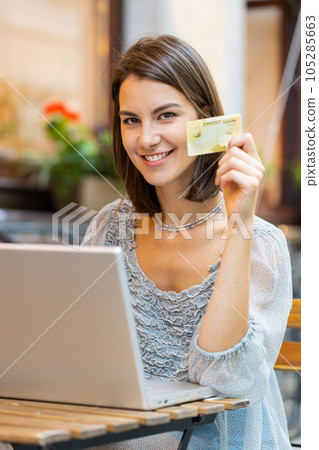 Young woman using credit bank card laptop computer while transferring money order food in cafeteria Young woman using credit bank card laptop computer while transferring money order food in cafeteria 105285663