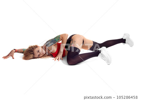Sexy blond twerk woman with tattoed body and long curly hair is posing in studio. Sexy blond twerk woman with tattoed body and long curly hair is posing in studio. 105286458