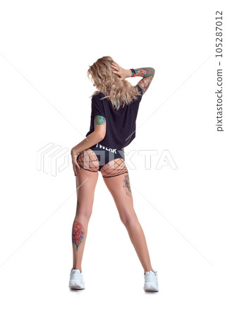 Beautiful blonde dancer woman in booty shorts and fishnet stand backwards isolated on white background 105287012