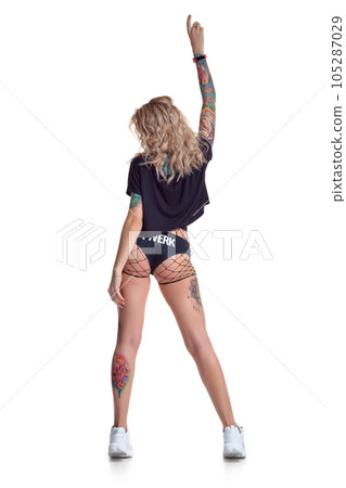 Beautiful blonde dancer woman in booty shorts and fishnet stand backwards isolated on white background 105287029