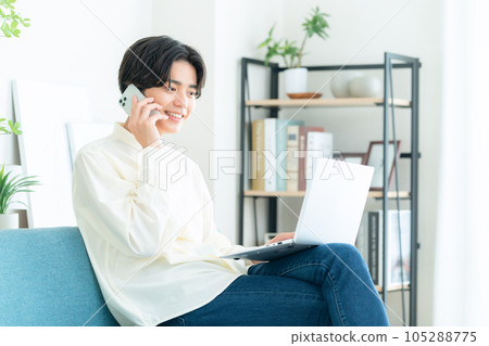 Young man sitting on a sofa in the living room and using a computer 105288775