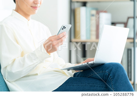 坐在客廳沙發上操作個人電腦的年輕人的身體部位 105288776