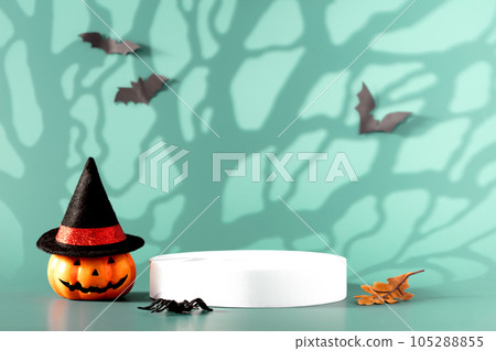 Creative Halloween composition with pumpkin, spiders, white podium and blue background. Modern Halloween aesthetic. 105288855