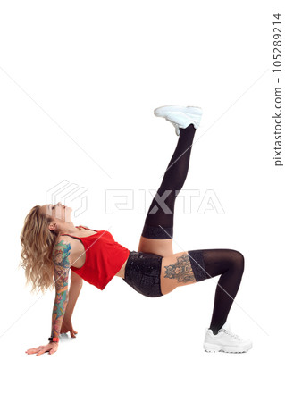 Sexy blond twerk woman with tattoed body and long curly hair is posing in studio. Sexy blond twerk woman with tattoed body and long curly hair is posing in studio. 105289214