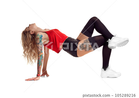 Sexy blond twerk woman with tattoed body and long curly hair is posing in studio. 105289216