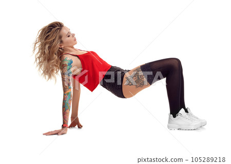 Sexy blond twerk woman with tattoed body and long curly hair is posing in studio. Sexy blond twerk woman with tattoed body and long curly hair is posing in studio. 105289218