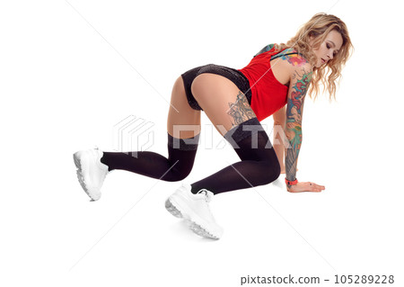 Sexy blond twerk woman with tattoed body and long curly hair is posing in studio. Sexy blond twerk woman with tattoed body and long curly hair is posing in studio. 105289228