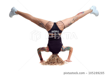 Sexy blond twerk woman with tattoed body and long curly hair is posing in studio. Sexy blond twerk woman with tattoed body and long curly hair is posing in studio. 105289285