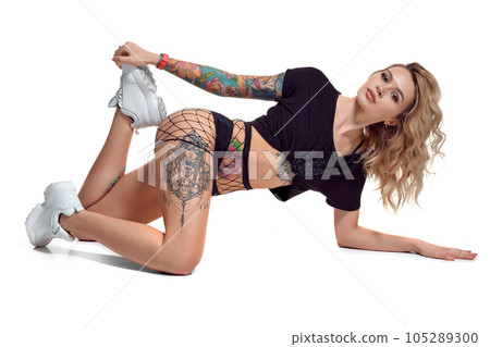 Sexy blond twerk woman with tattoed body and long curly hair is posing in studio. 105289300