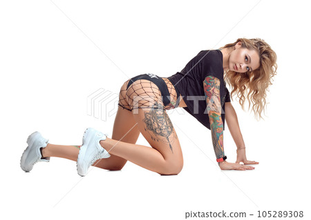 Sexy blond twerk woman with tattoed body and long curly hair is posing in studio. Sexy blond twerk woman with tattoed body and long curly hair is posing in studio. 105289308