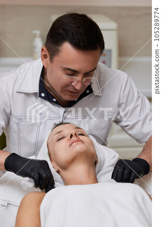 beautician cleanses skin of woman with cotton sponge. . beautician cleanses skin of woman with cotton sponge. . 105289774