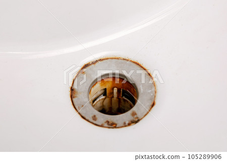 Dirty and rusty washbasin, close up view. Metal drain hole with red rust stain. Corrosion, unsanitary. Stained bathroom plumbing. Cleaning service needed. Unclean home. Dirty and rusty washbasin, close up view. Metal drain hole with red rust stain. Corrosion, unsanitary. Stained bathroom plumbing. Cleaning service needed. Unclean home. 105289906