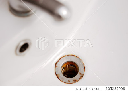 Dirty and rusty washbasin, close up view. Metal drain hole with red rust stain. Corrosion, unsanitary. Stained bathroom plumbing. Cleaning service needed. Unclean home. Dirty and rusty washbasin, close up view. Metal drain hole with red rust stain. Corrosion, unsanitary. Stained bathroom plumbing. Cleaning service needed. Unclean home. 105289908