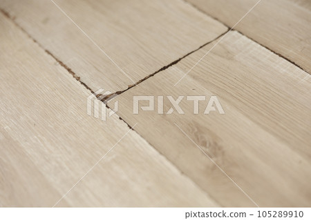 Swollen and dirty laminate floor, close up view. Moisture damage. Laminate flooring has swelled. Damaged laminate planks. Home, property insurance. 105289910