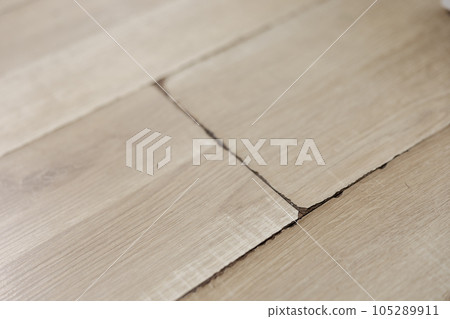 Swollen and dirty laminate floor, close up view. Moisture damage. Laminate flooring has swelled. Damaged laminate planks. Home, property insurance. 105289911