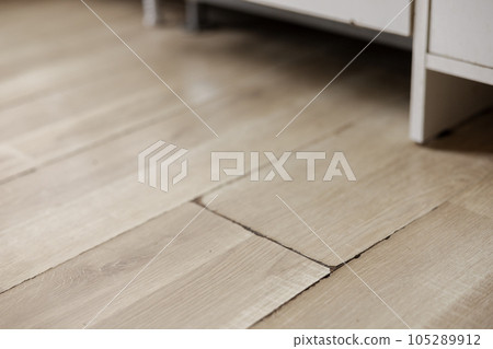 Swollen and dirty laminate floor, close up view. Moisture damage. Laminate flooring has swelled. Damaged laminate planks. Home, property insurance. 105289912