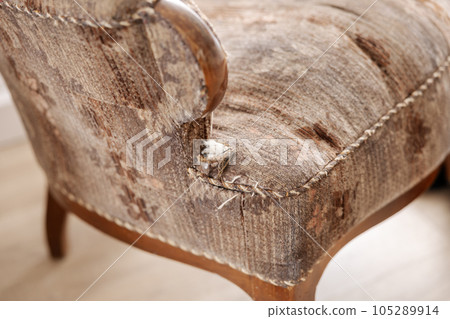 Old, damaged vintage armchair with holes in seat. Antique couch with ripped fabric. Upholstered furniture restoration service. Furniture repair. Old, damaged vintage armchair with holes in seat. Antique couch with ripped fabric. Upholstered furniture restoration service. Furniture repair. 105289914