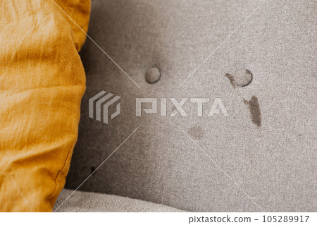 Dirty sofa, close up view. Stains on home textile. Upholstered furniture cleaning concept. Dirty couch, chemnical cleaning needed. Dirt, mess. Care of home fabrics. 105289917