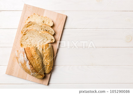 Freshly baked bread slices on cutting board against white wooden background. top view Sliced bread Freshly baked bread slices on cutting board against white wooden background. top view Sliced bread 105290086