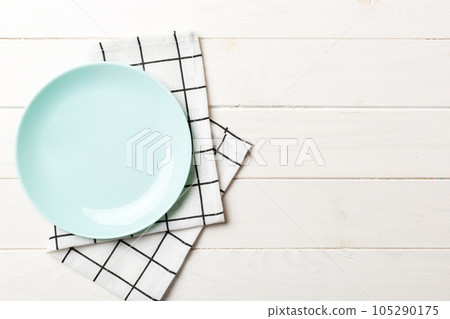 Top view on colored background empty round blue plate on tablecloth for food. Empty dish on napkin with space for your design 105290175