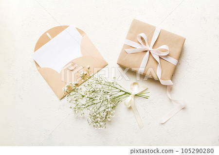 Wedding mockup with white paper list and flowers gypsophila on colored table top view flat lay. Blank greeting cards and envelopes. Beautiful floral pattern. Flat lay style Wedding mockup with white paper list and flowers gypsophila on colored table top view flat lay. Blank greeting cards and envelopes. Beautiful floral pattern. Flat lay style 105290280