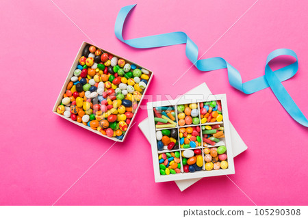 Set of different sweet candy in a paper box with a satin ribbon on a colored background. Holiday concept 105290308