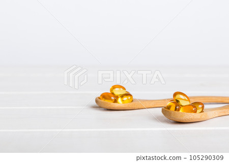 Vitamin omega capsules in a spoon on a colored background. Pills served as a healthy meal. Red soft gel vitamin supplement capsules on spoon Vitamin omega capsules in a spoon on a colored background. Pills served as a healthy meal. Red soft gel vitamin supplement capsules on spoon 105290309