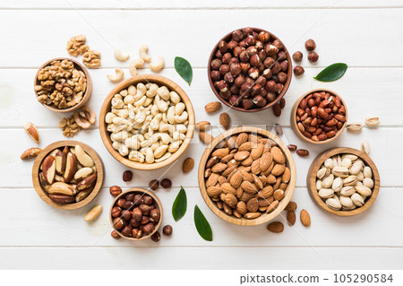mixed nuts in wooden bowl. Mix of various nuts on colored background. pistachios, cashews, walnuts, hazelnuts, peanuts and brazil nuts mixed nuts in wooden bowl. Mix of various nuts on colored background. pistachios, cashews, walnuts, hazelnuts, peanuts and brazil nuts 105290584