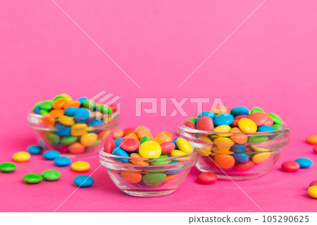 Multicolored candies in a bowl on a colored background. birthday and holiday concept. Top view with copy space 105290625