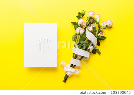 Greeting holiday card mockup with fresh roses on colored table background, mock up with copy space for design 105290643