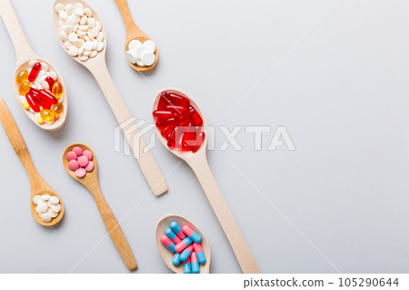 Vitamin capsules in a spoon on a colored background. Pills served as a healthy meal. Red soft gel vitamin supplement capsules on spoon Vitamin capsules in a spoon on a colored background. Pills served as a healthy meal. Red soft gel vitamin supplement capsules on spoon 105290644