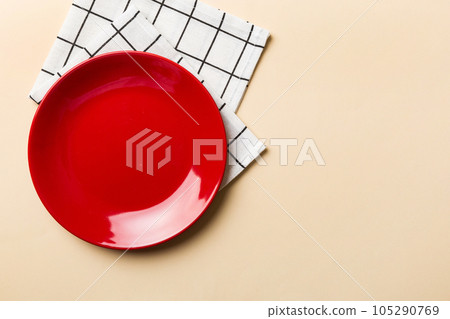 Top view on colored background empty round red plate on tablecloth for food. Empty dish on napkin with space for your design 105290769