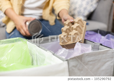Female sitting at home separating paper and plastic waste. Female sitting at home separating paper and plastic waste. 105290792