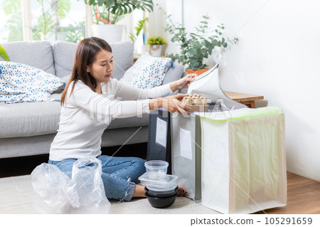 Asian young female sitting at home separating paper and plastic waste 105291659