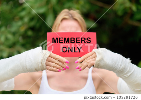 Women's hands in a cast hold a red card with the text MEMBERS ONLY Women's hands in a cast hold a red card with the text MEMBERS ONLY 105291726