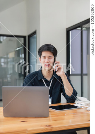 Smiling businessman talking on phone, sitting at desk with laptop, friendly manager consulting customer by phone, happy man chatting with friends from work 105292009
