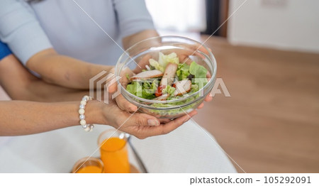 Two happy retired Asian female friends are enjoying their healthy salad together 105292091
