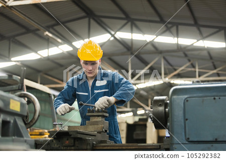 Male workers wear yellow hard hat holding wrench working on repairing factory machinery. 105292382