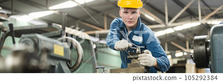 Male workers wear yellow hard hat holding wrench working on repairing factory machinery. 105292384