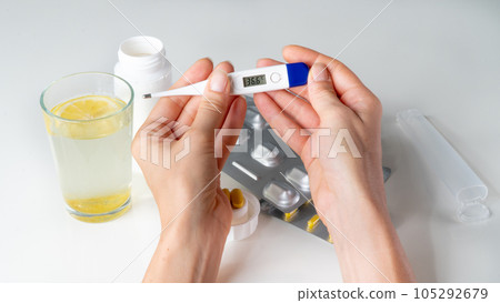 Temperature on the thermometer 36.6 - a recovered person against the background of tablets 105292679