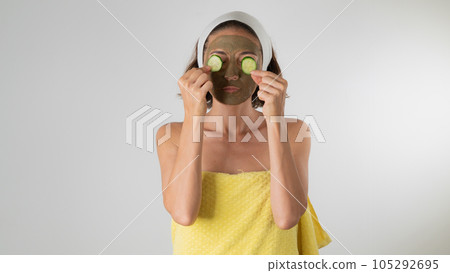 The woman makes a face mask and removes bags under the eyes with cucumber - self-care at home 105292695