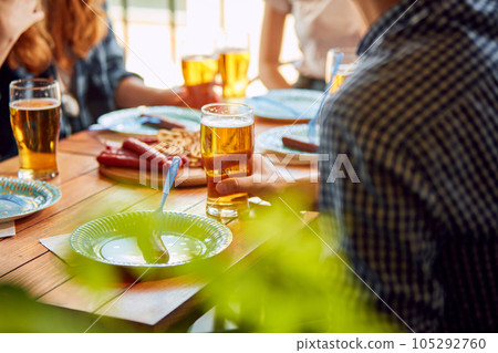 Young people, friends meeting together on warm day, sitting in pub, drinking delicious lager beer and having pleasant time together Young people, friends meeting together on warm day, sitting in pub, drinking delicious lager beer and having pleasant time together 105292760