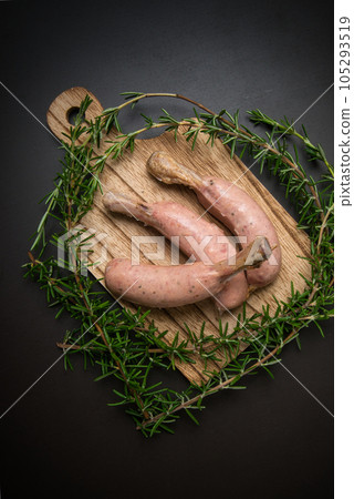 Place the sausage on the bone on a cutting board and garnish with rosemary. Place the sausage on the bone on a cutting board and garnish with rosemary. 105293519