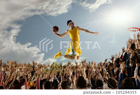 Collage with basketball player with ball in hands jumping high over hands of fans scoring a goal. 105294355